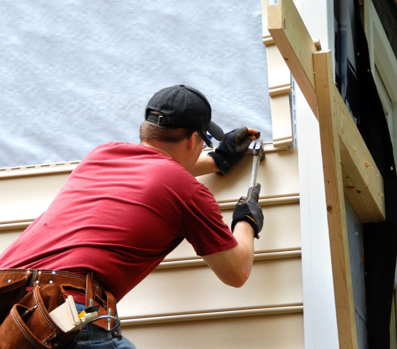 Kutsch Roofing technician sealing vinyl siding near a window frame