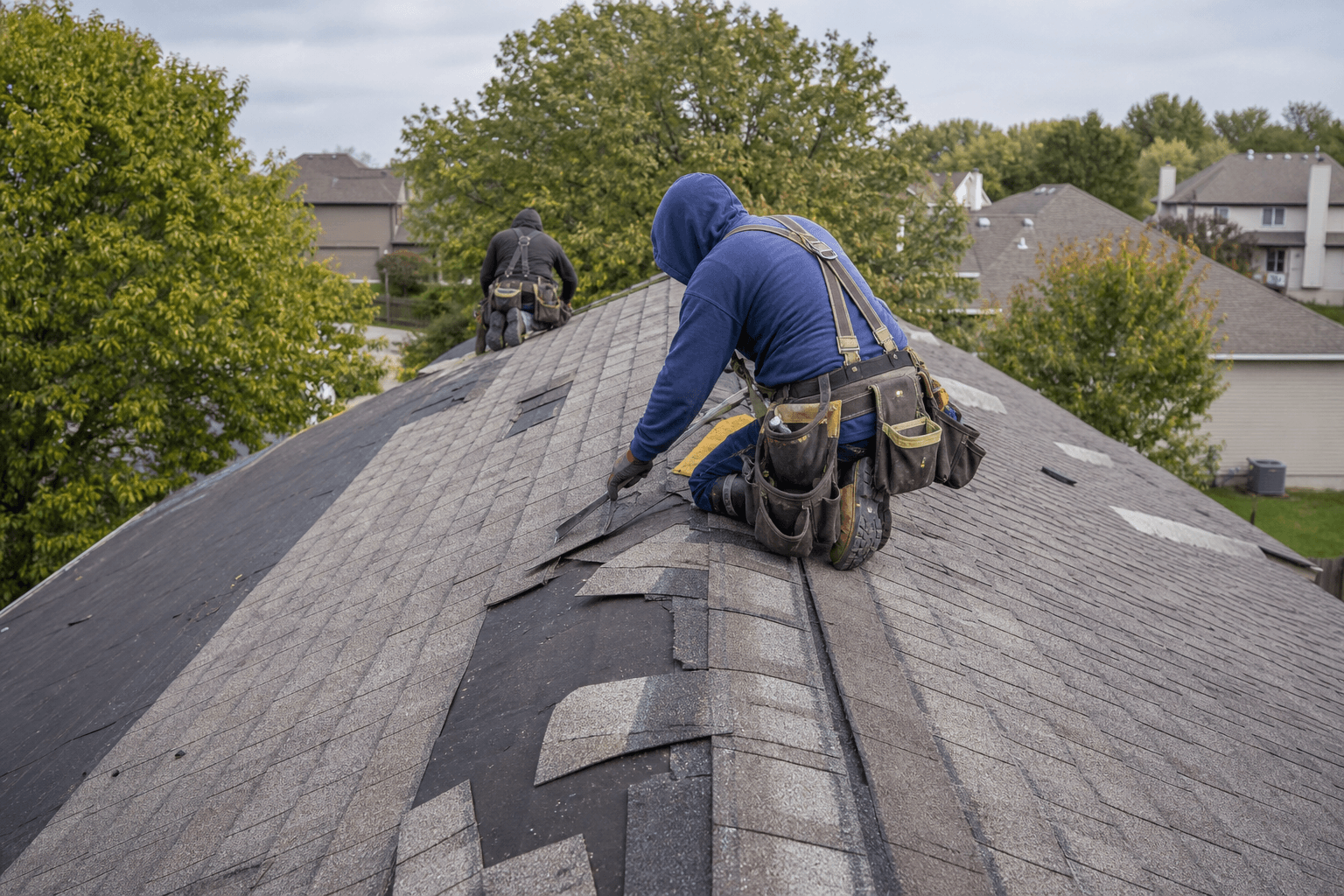 Professional roofers repairing damaged shingles on a residential roof in Omaha, Nebraska