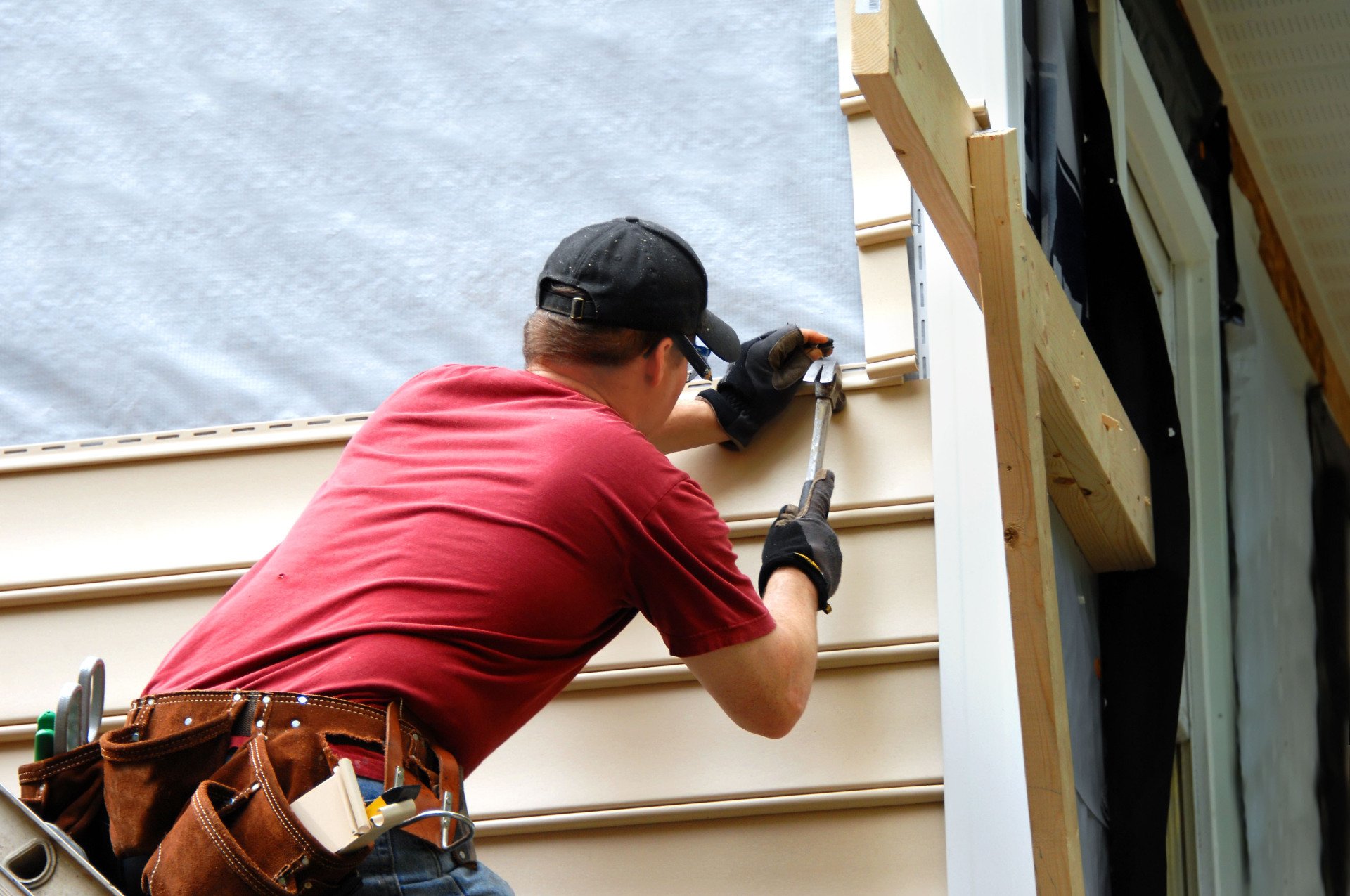 Kutsch Roofing technician sealing vinyl siding near a window frame